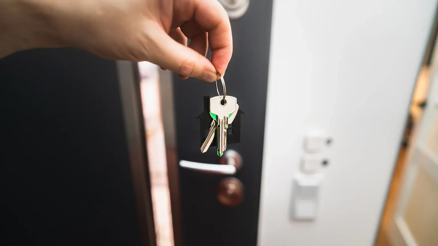 Mano entregando las llaves de una vivienda en la puerta